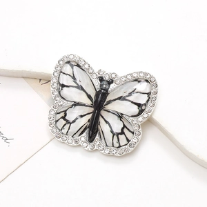 Détail d'un charm papillon argenté avec ailes noir et blanc et strass étincelants