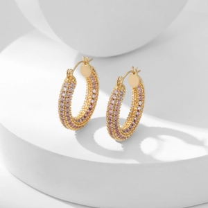Gold-plated hoop earrings with micro-paved purple cubic zirconia on a minimalist white pedestal