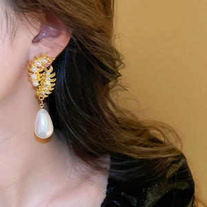 Detail of vintage gold earring with wheat leaf design, rhinestones and drop pearl