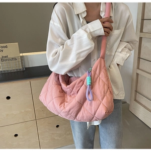 Detailed view of pink quilted tote bag with diamond stitching and decorative woven charm