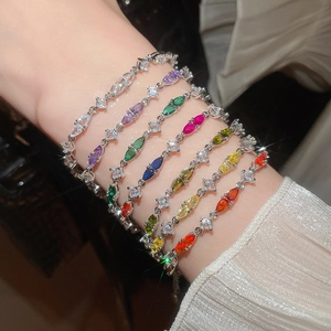 Close-up of sparkling colorful zircon teardrop bracelet on wrist with elegant silk sleeve