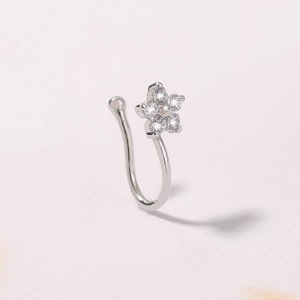 Detailed macro view of a silver flower nose ring with five clear crystals on white background