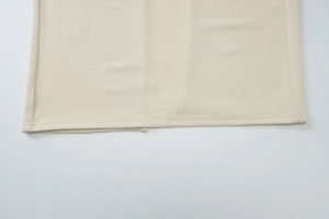 Détail de la robe d'été beige montrant la texture en maille et l'ourlet fendu cousu