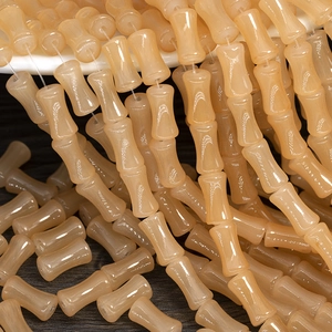 Detailed view of beige bamboo-shaped glass beads cascading from a container
