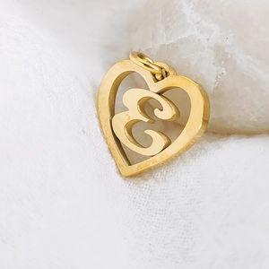 Detailed close-up of a golden stainless steel heart-shaped pendant with letter E.