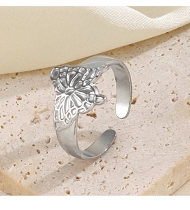 Detailed close-up of a silver butterfly embossed adjustable ring on a beige stone base