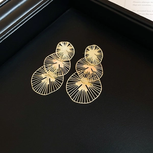 Vue détaillée des boucles d'oreilles dorées avec anneaux ajourés sur un plateau noir