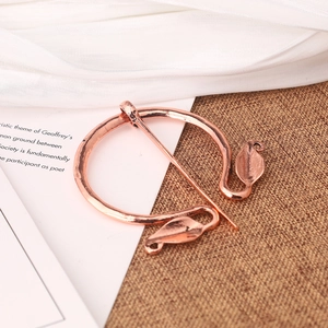 Close-up of rose gold vintage Viking brooch on parchment with textured burlap background