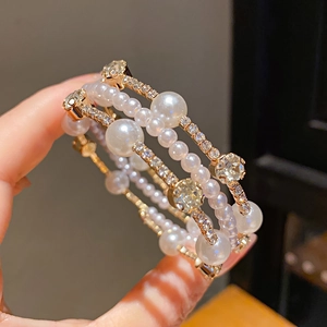 Detailed close-up of multi-layer gold pearl bracelet with sparkling rhinestones decoration