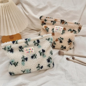 Detail of plush lamb wool cosmetic bags featuring delicate floral patterns and soft textures