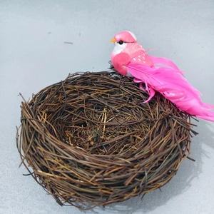 Detail of pink artificial bird with feathers perched on a rustic vine twig nest