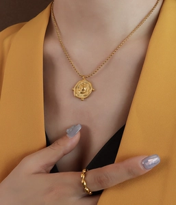 Detail of vintage irregular coin pendant necklace and textured gold ring on model