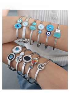 Detailed stack of silver charm bracelets with Tree of Life and Evil Eye enamel motifs