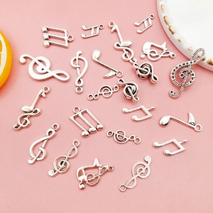 Detailed view of assorted silver music note charms for DIY jewelry on pink background