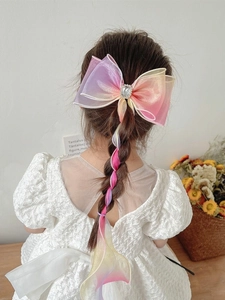 Detail of girl wearing gradient bow hair clip with long ribbons and rhinestone accents