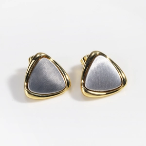 Detail of two-tone gold and silver triangle earrings with brushed metal texture