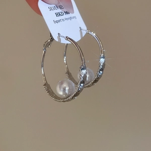 Detail of 925 silver pearl hoop earrings with textured metal finish and large white pearls