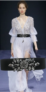 Detail of wide elastic black belt with large floral rhinestone buckle on female model