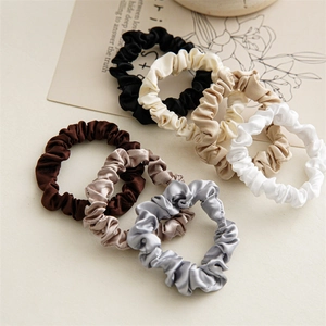 Macro shot of 7 assorted earth-tone satin scrunchies with elegant silk-like glossy finish