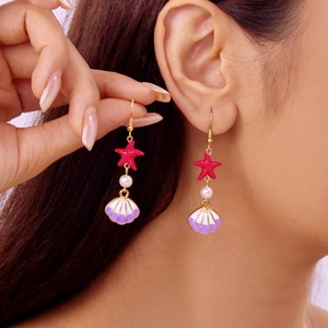 Detail of red starfish and seashell drop earrings with pearls on a model ear