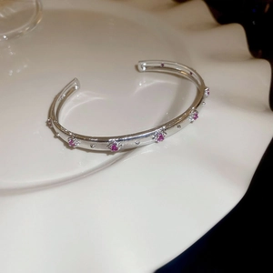 Detailansicht eines mehrlagigen Silberarmbands mit rosa Edelsteinen und floralem Diamantbesatz