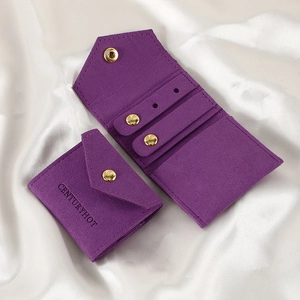 Macro shot of purple suede jewelry roll pouch with gold snap button on white silk fabric
