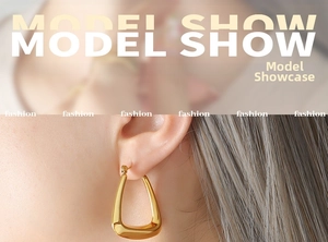 Close-up of polished U-shaped 18k gold-plated earrings worn by a model in French style