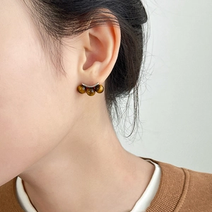 Close-up of tiger eye stone earrings with three brown beads on a silver curved base