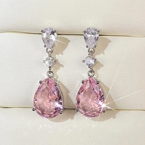 Macro shot of elegant pear-cut pink zircon drop earrings on a white jewelry display