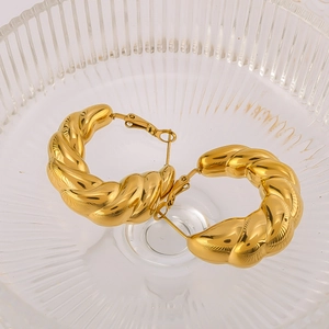 Golden croissant-textured hoop earrings in stainless steel on a clear glass tray