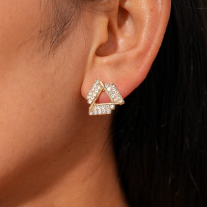 Close-up of geometric layered gold triangle earrings with sparkling white crystals