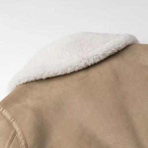 Détail du revers en laine d'agneau blanche et texture de la veste en daim kaki