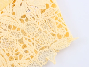 Macro detail of elegant yellow lace fabric with intricate floral patterns and mesh texture