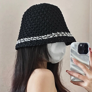 Close-up of handmade crochet texture and white wavy trim on black straw bucket hat