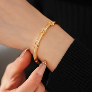 Detail of 18k gold plated X-shaped buckle bracelet with pavé cubic zirconia inlay