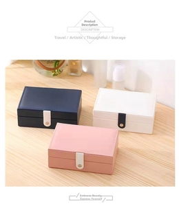 Close-up of portable PU leather jewelry cases in navy, white, and pink on a wooden desk