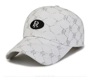 Close-up of white baseball cap with grey letter patterns and silver metal logo on front