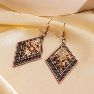 Ethnic bronze rhombus earrings with wooden beads on silk background, vintage geometric style