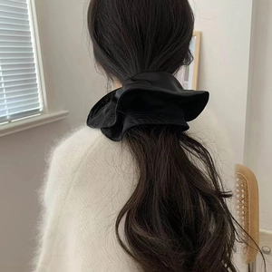 Close-up of black satin oversized scrunchie on a ponytail with soft pleated texture