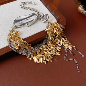 Detail of layered gold leaf and silver metal pendant bracelet on rustic wooden tray