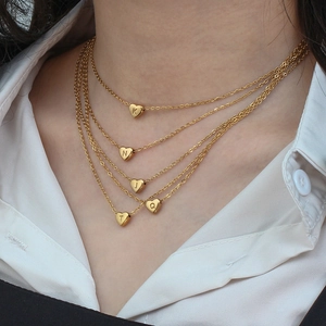 Colliers dorés avec pendentifs cœur et gravure initiale portés par un mannequin