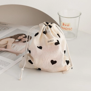 Macro shot of drawstring storage bag with heart pattern and textured cream fabric detail