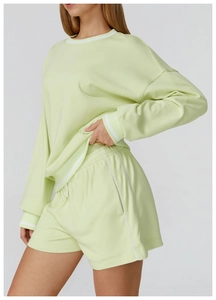 Dettaglio degli shorts in maglia verde chiaro con strisce laterali bianche e tessuto a nido