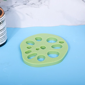 Detailed view of light green lotus root shaped silicone heat resistant coaster on blue desk