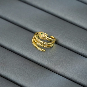 Close-up of golden snake ring with zircon inlay and green gemstone eyes detailing