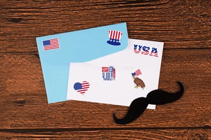 Detail view of USA 250th Independence Day stickers on blue envelopes over wooden table