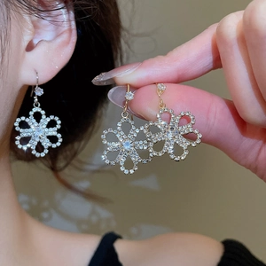 Detailed view of flower-shaped crystal dangle earrings in gold and silver finishes