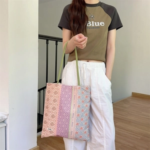 Gros plan d'un sac cabas en toile à patchwork floral avec des poignées vert herbe