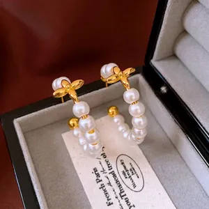 Elegant gold-plated C-shape hoop earrings with white pearls and clover charm detail