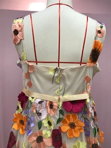 Détail de la broderie florale multicolore et du ruban de satin champagne sur la robe